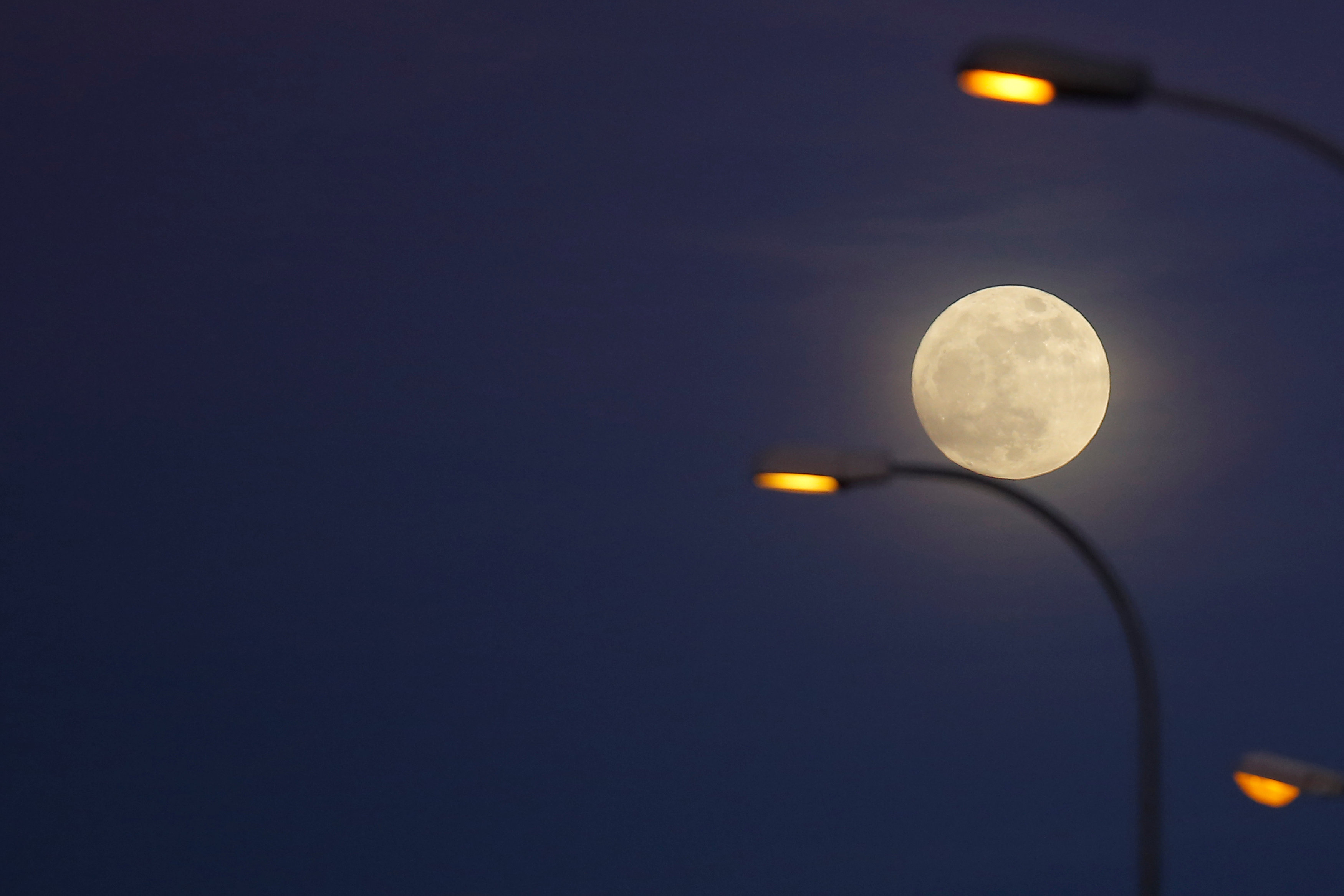 The 'supermoon' full moon is seen rising behind street lights in Ronda