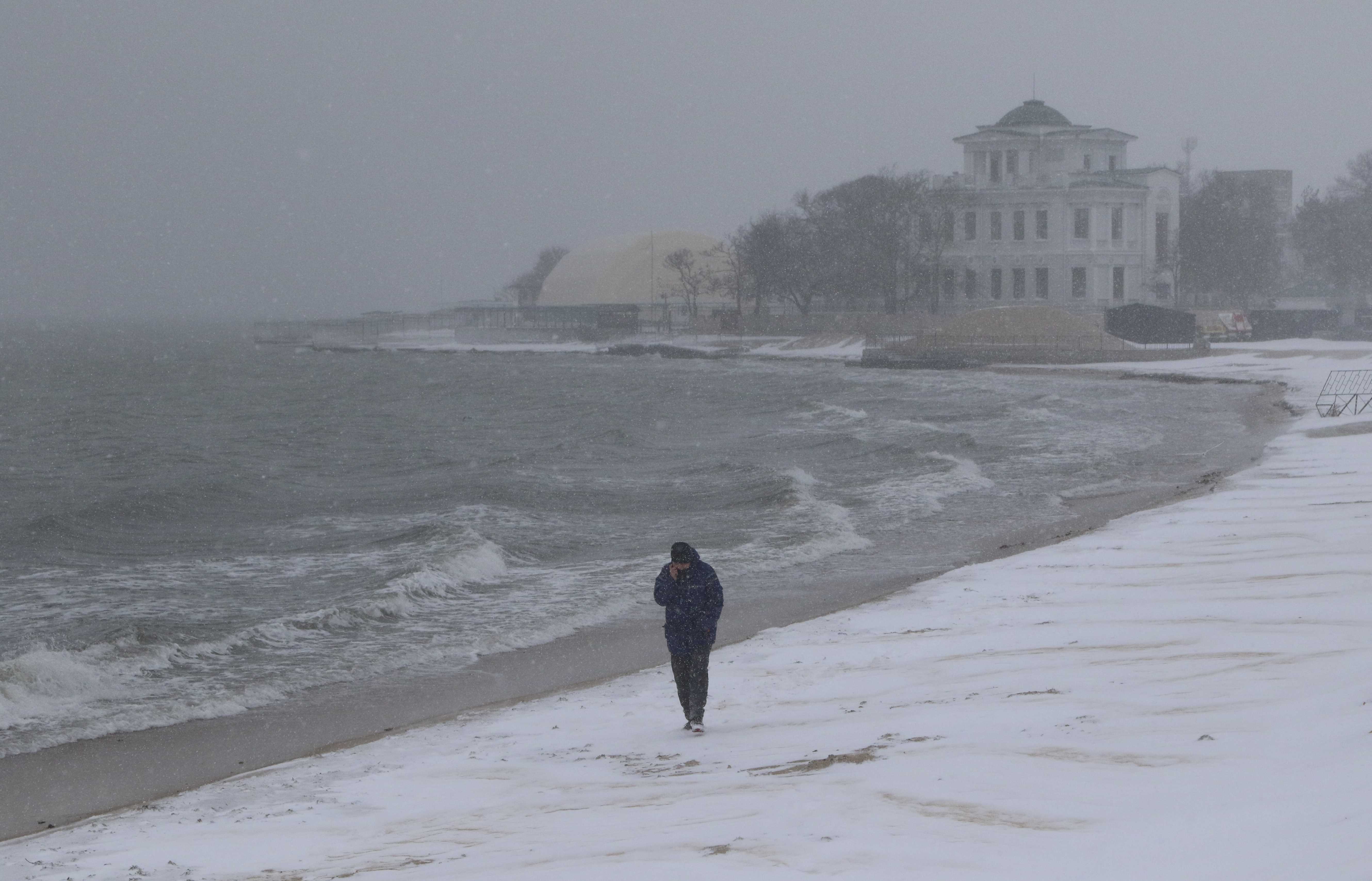 A man walks along the beach during a heavy snowfall in Yevpatoriya