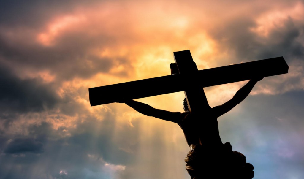 Christian cross with Jesus Christ statue over stormy clouds