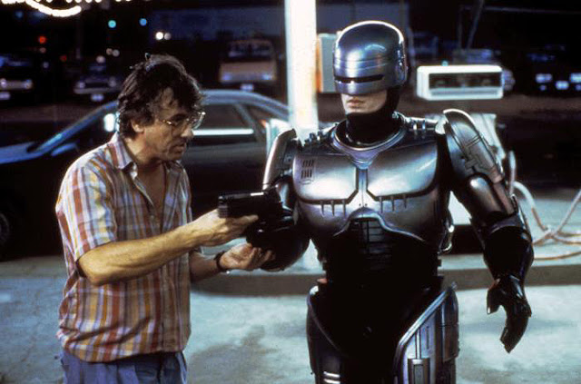 El director Paul Verhoeven le da instrucciones al actor Peter Weller sobre cómo RoboCop debe apuntar su arma.