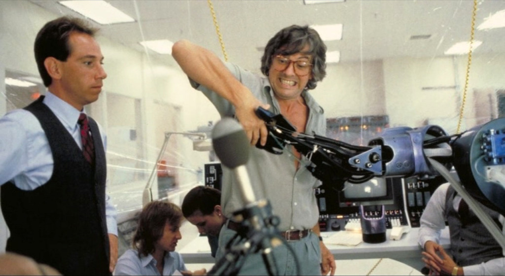 El director Paul Verhoeven le enseña al actor Miguel Ferrer (Bob Morton) cómo se rodará la escena en que su personaje estrecha la mano robótica de RoboCop.