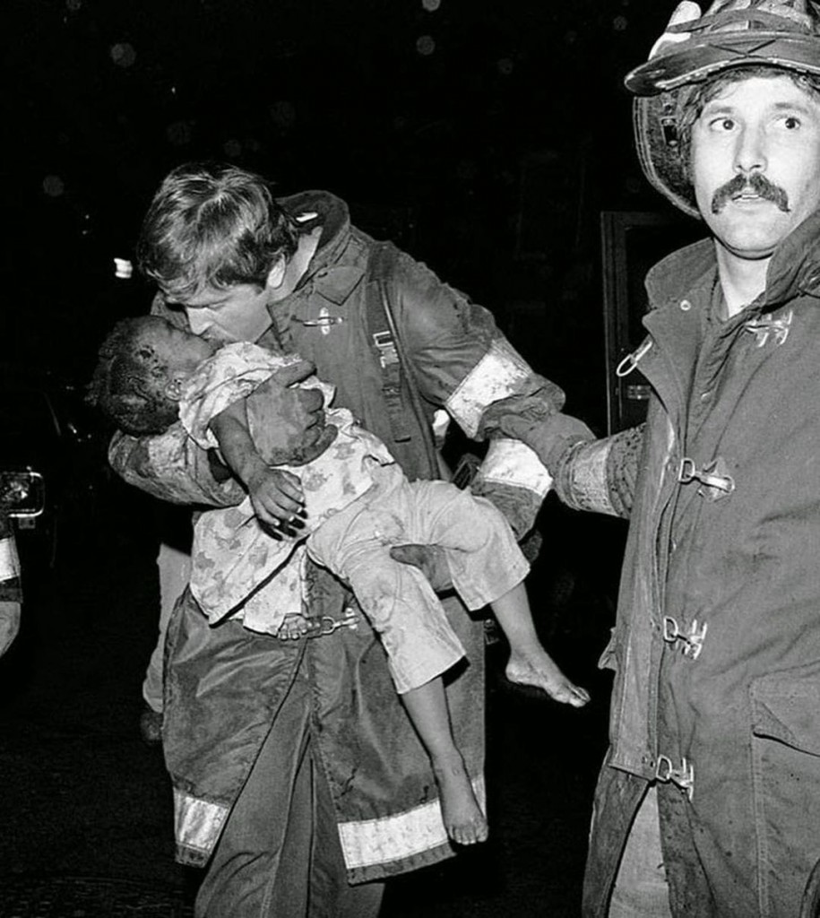 Fotografía donde aparece la pequeña Tiare Jones recibiendo  la ayuda de los bomberos, poco después del fatal momento del derrumbe de la escalera de incendios del edificio siniestrado de Boston. 